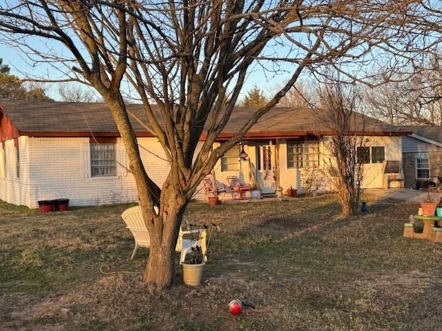 back of property featuring brick siding and a yard