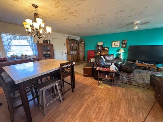 dining space featuring wood finished floors and ceiling fan with notable chandelier