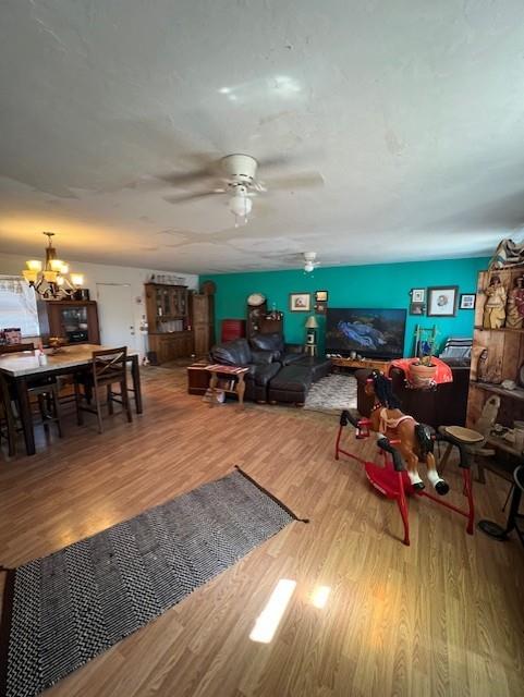 living room featuring ceiling fan with notable chandelier and wood finished floors