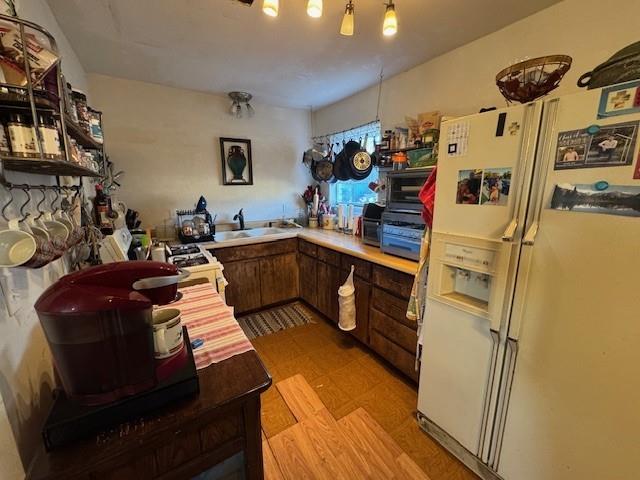 kitchen with white appliances, light wood-style flooring, light countertops, and a sink