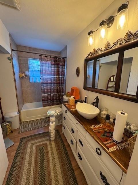 full bath with toilet, wood finished floors, shower / bath combo with shower curtain, and vanity