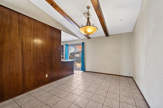 tiled spare room featuring a textured ceiling, lofted ceiling with beams, wooden walls, and sink