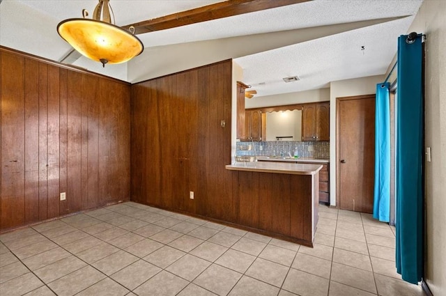 kitchen with vaulted ceiling, light tile patterned floors, a textured ceiling, tasteful backsplash, and kitchen peninsula