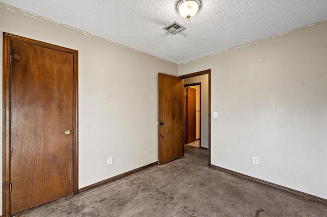 unfurnished room with concrete flooring and a textured ceiling