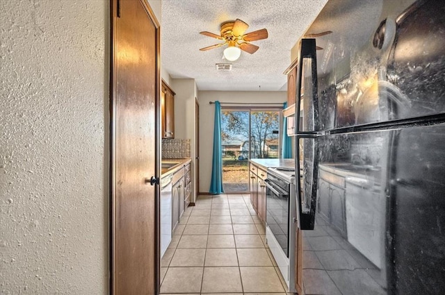 kitchen featuring ceiling fan, a textured ceiling, white appliances, decorative backsplash, and light tile patterned floors