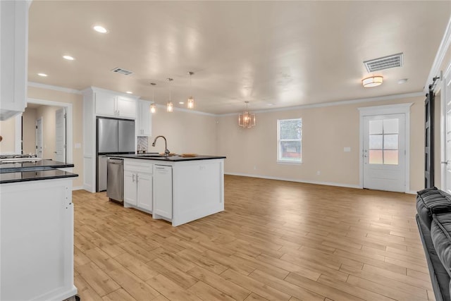 kitchen with white cabinets, dishwasher, pendant lighting, and a center island with sink