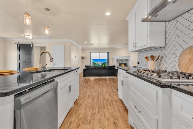 kitchen featuring sink, stainless steel appliances, wall chimney range hood, white cabinets, and light wood-type flooring