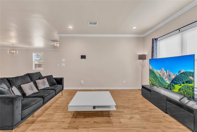 living room featuring light hardwood / wood-style floors, ornamental molding, and an inviting chandelier