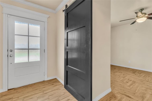 doorway to outside with ceiling fan, a barn door, crown molding, and a wealth of natural light