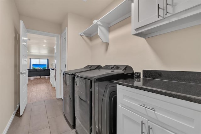 laundry room with washing machine and clothes dryer, cabinets, and light hardwood / wood-style floors