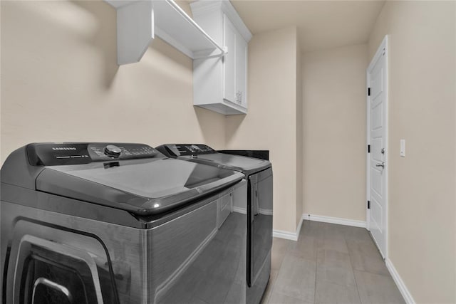 washroom with washer and dryer, cabinets, and light wood-type flooring