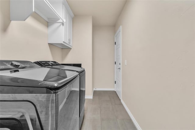 laundry room featuring cabinets, washer and dryer, and light wood-type flooring