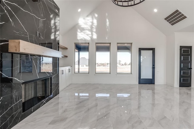 unfurnished living room with high vaulted ceiling, tile walls, and a premium fireplace