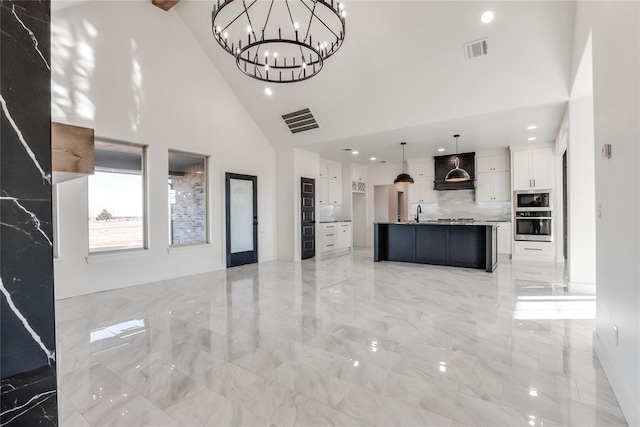 unfurnished living room with high vaulted ceiling and an inviting chandelier