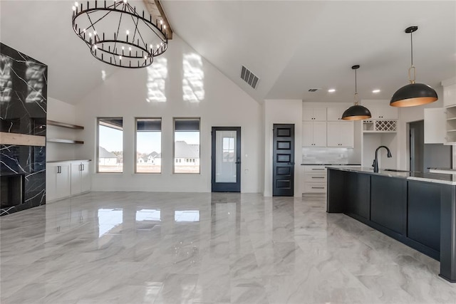 kitchen with white cabinets, a fireplace, hanging light fixtures, and high vaulted ceiling