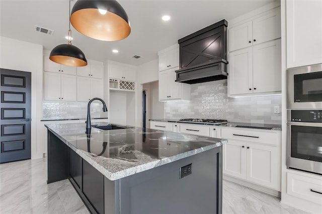 kitchen with decorative backsplash, white cabinetry, an island with sink, and appliances with stainless steel finishes