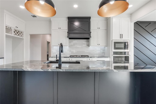 kitchen featuring white cabinets, stainless steel appliances, and light stone counters