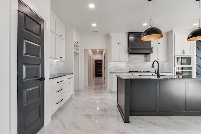 kitchen featuring built in microwave, white cabinetry, dark stone counters, and decorative light fixtures