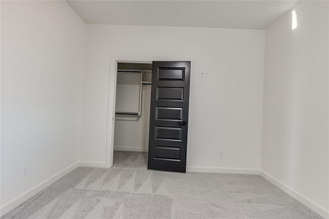 unfurnished bedroom with light carpet and a closet