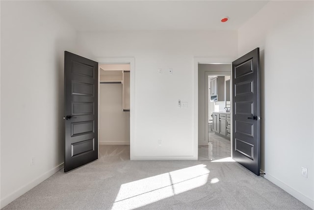 unfurnished bedroom featuring a walk in closet and light carpet