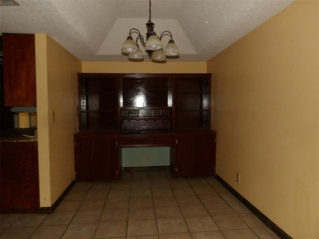 unfurnished dining area featuring a textured ceiling, a notable chandelier, and light tile patterned flooring