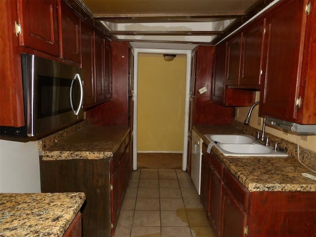 kitchen with dishwasher, light stone counters, light tile patterned floors, and sink