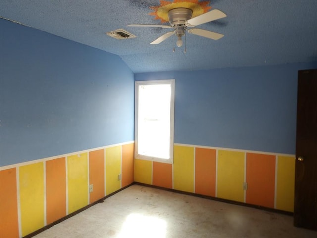 spare room featuring lofted ceiling, ceiling fan, and a textured ceiling