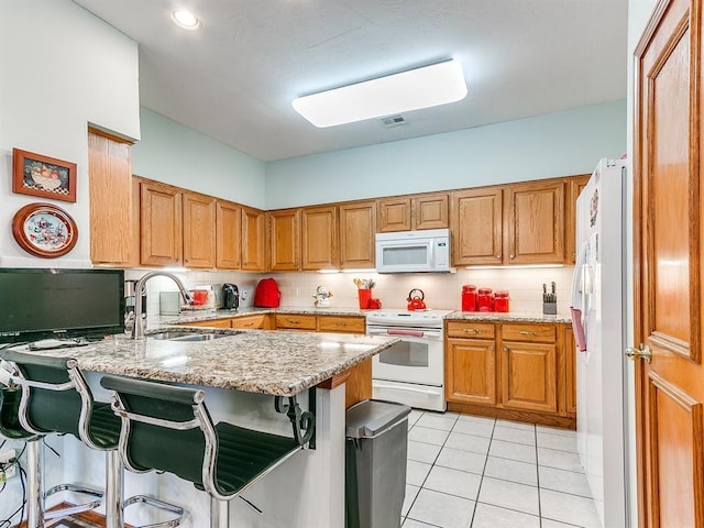 kitchen featuring a breakfast bar area, kitchen peninsula, sink, and white appliances