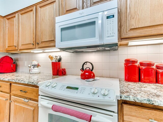 kitchen with light stone countertops, white appliances, and tasteful backsplash