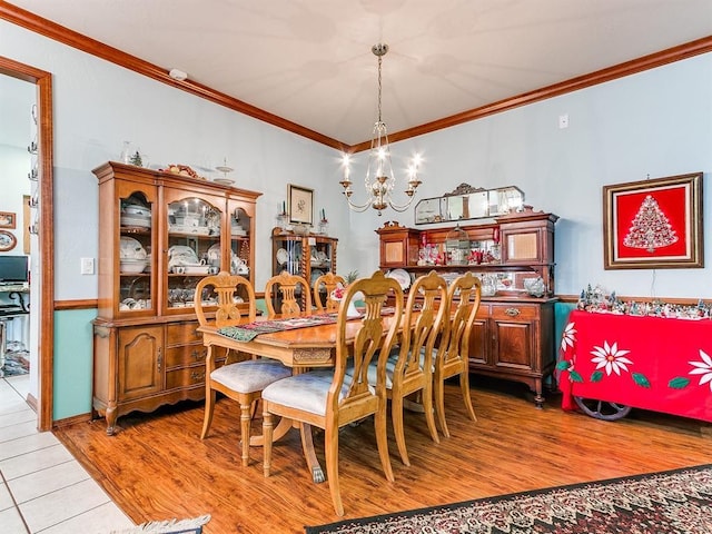 dining room featuring light wood-type flooring, an inviting chandelier, and crown molding