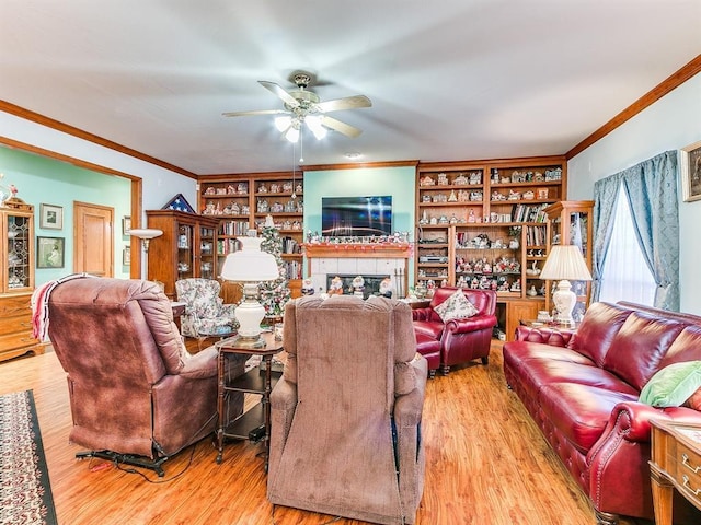 living room with ceiling fan, light wood-type flooring, built in features, and a fireplace