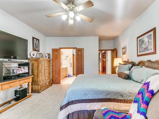 bedroom with ceiling fan, light colored carpet, and ensuite bath