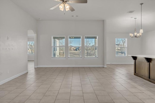 tiled spare room with ceiling fan with notable chandelier