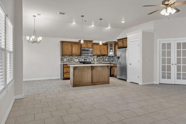 kitchen featuring tasteful backsplash, a center island with sink, pendant lighting, stainless steel appliances, and ceiling fan with notable chandelier