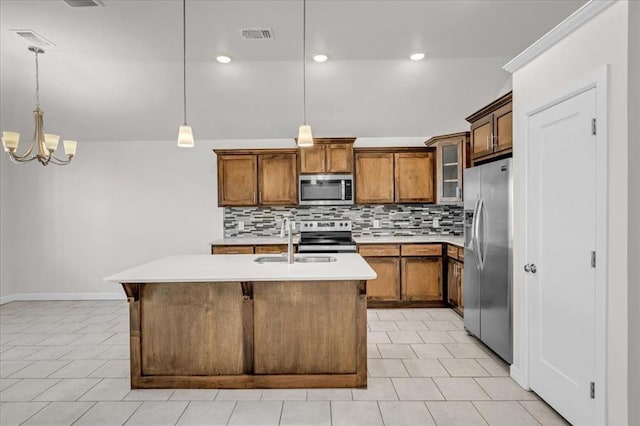 kitchen with hanging light fixtures, an island with sink, appliances with stainless steel finishes, and sink