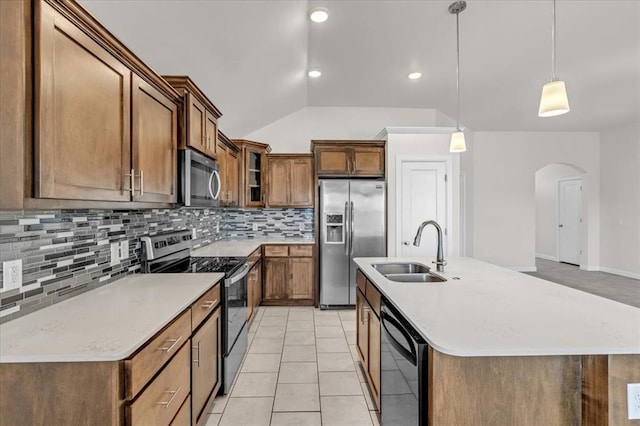 kitchen with appliances with stainless steel finishes, pendant lighting, sink, backsplash, and a kitchen island with sink