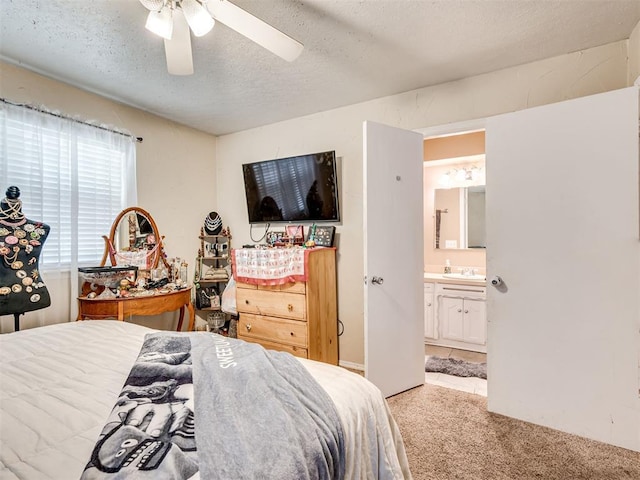 carpeted bedroom with a textured ceiling, ensuite bath, ceiling fan, and sink