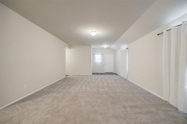 spare room featuring light carpet and lofted ceiling