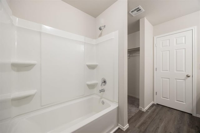 bathroom featuring hardwood / wood-style floors and washtub / shower combination