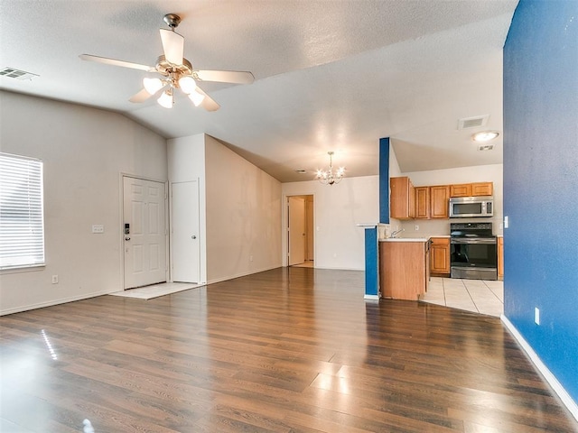 unfurnished living room featuring ceiling fan with notable chandelier, a textured ceiling, vaulted ceiling, and light hardwood / wood-style flooring