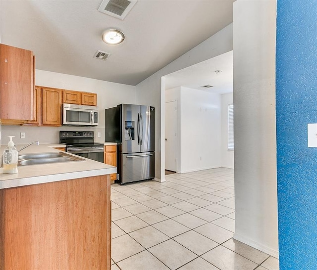 kitchen with light tile patterned floors, stainless steel appliances, and sink