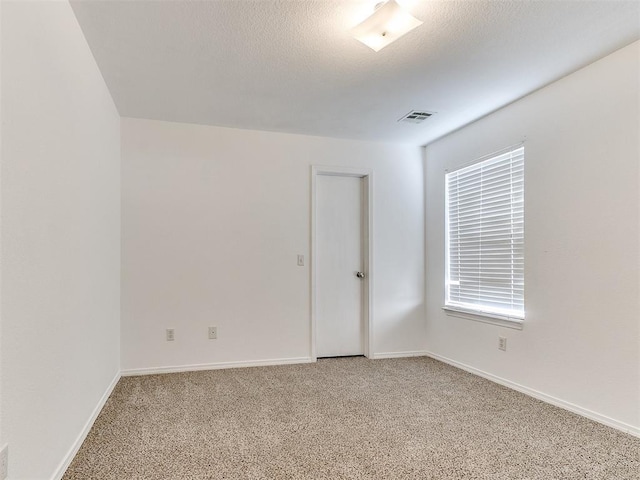 carpeted spare room with a textured ceiling