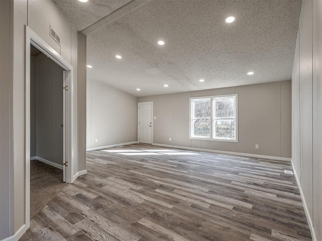 empty room with wood-type flooring and a textured ceiling