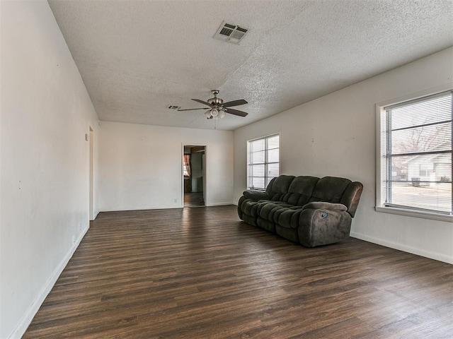 living room with a textured ceiling, dark hardwood / wood-style flooring, and ceiling fan