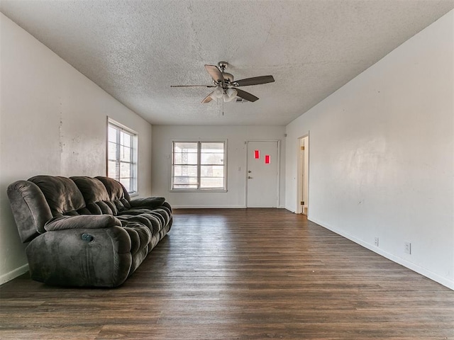 unfurnished living room with ceiling fan, dark wood-type flooring, and a textured ceiling