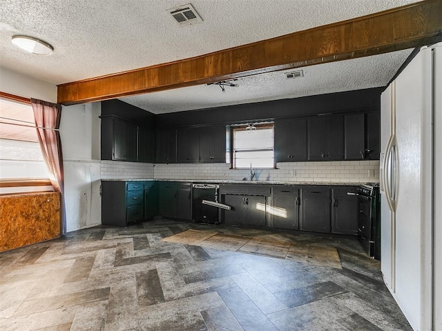 kitchen with decorative backsplash, a textured ceiling, white fridge, and black range