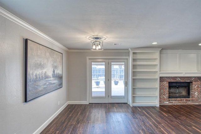 unfurnished living room with dark wood-style flooring, french doors, ornamental molding, a brick fireplace, and baseboards