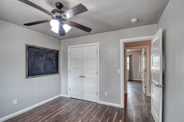 unfurnished bedroom with a closet, baseboards, and dark wood-style flooring