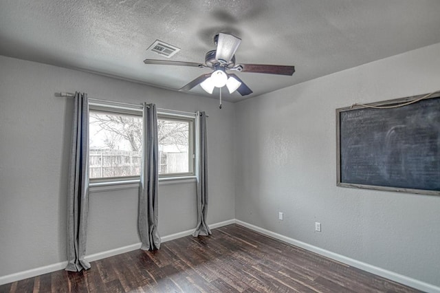 unfurnished room featuring a textured ceiling, a ceiling fan, visible vents, baseboards, and dark wood finished floors