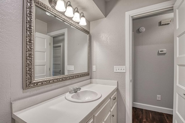 bathroom featuring a textured wall, wood finished floors, vanity, and baseboards